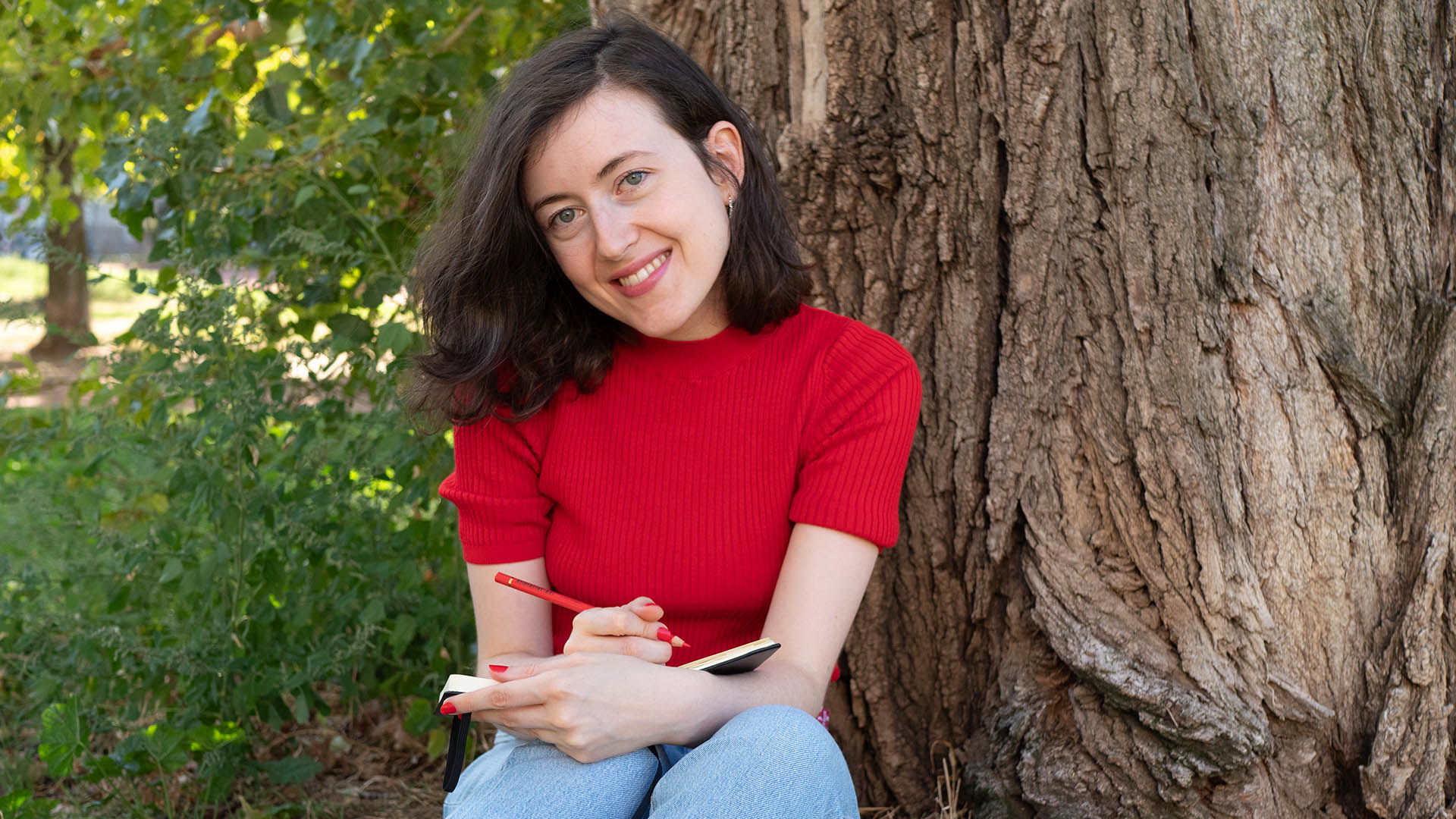 Une photo de moi-même, assise près d'un arbre et dessinant, pour illustrer mon article "Comment retrouver la motivation et l'envie de créer"