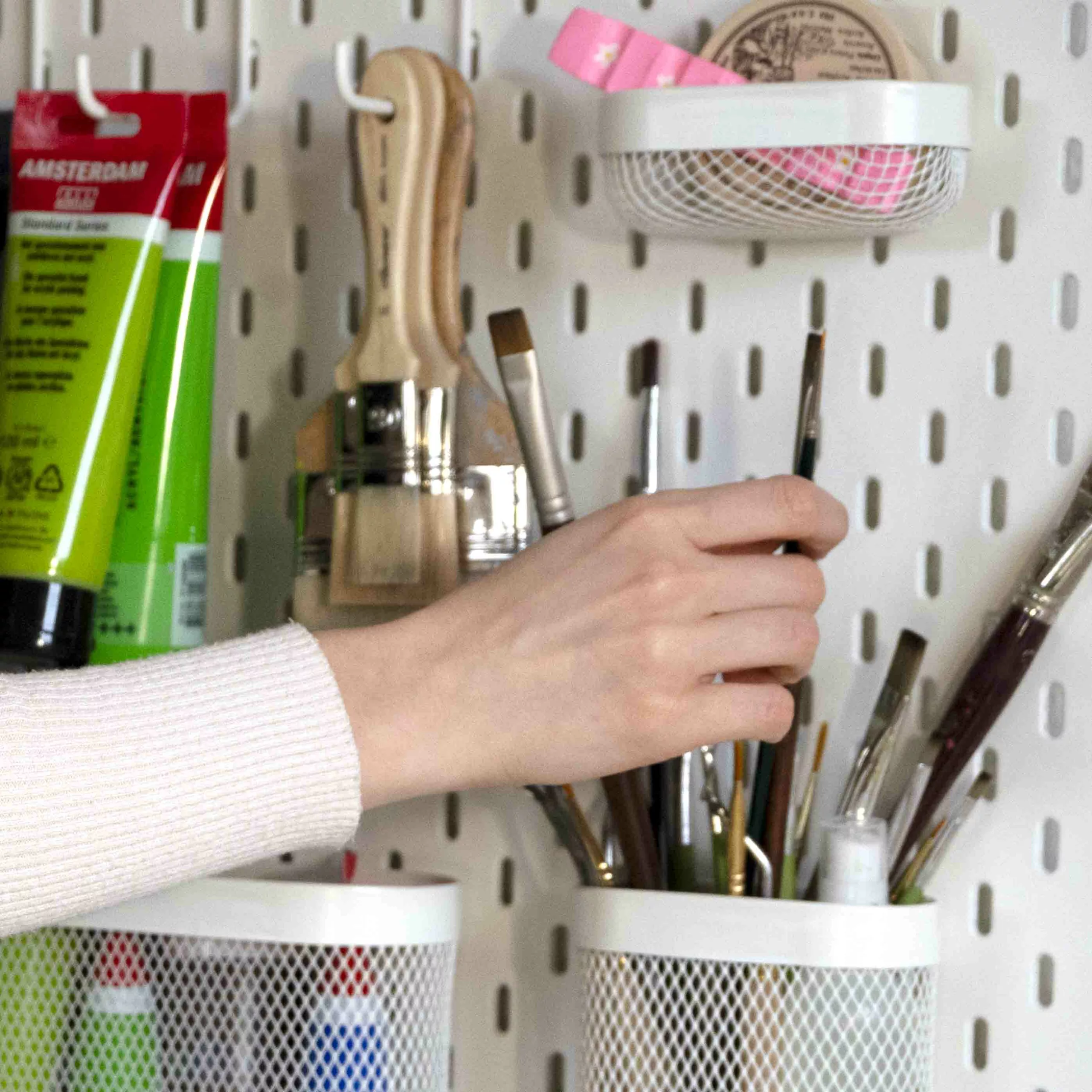 Close-up of the hand of Enolie, French artist and painter, choosing her brushes with which to paint.