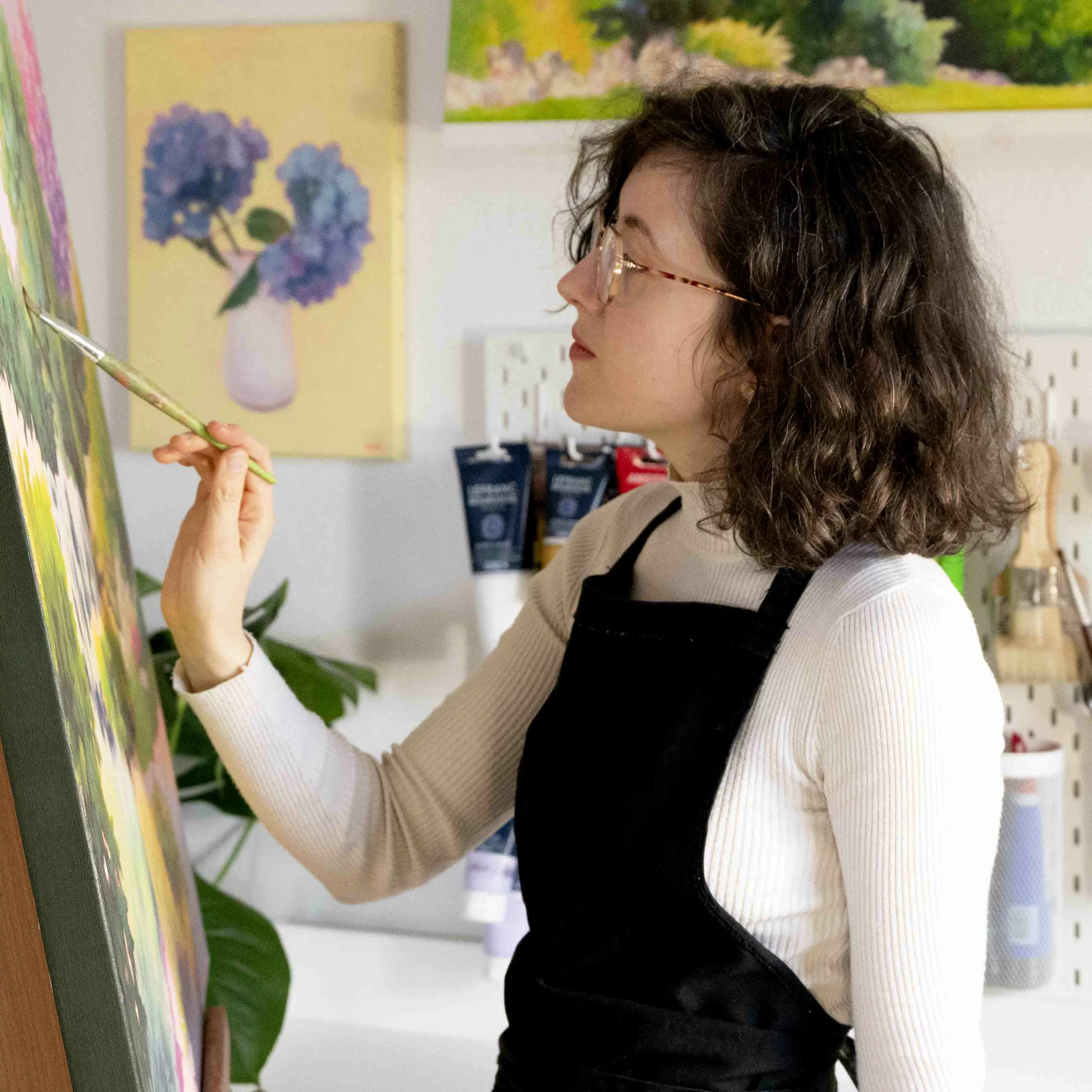 Photo of Enolie, a French artist and painter, taken while she was painting in her art studio.